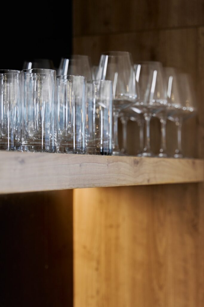 A bunch of glasses are lined up on a shelf