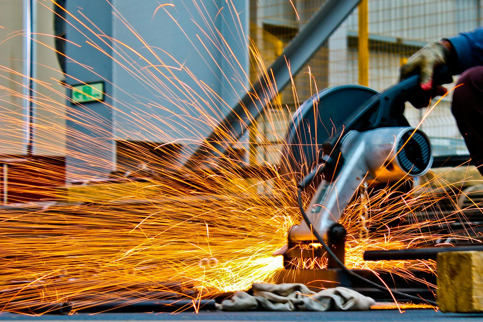 A worker operates a grinder cutting metal, creating a vibrant display of sparks in an industrial setting. what is construction management