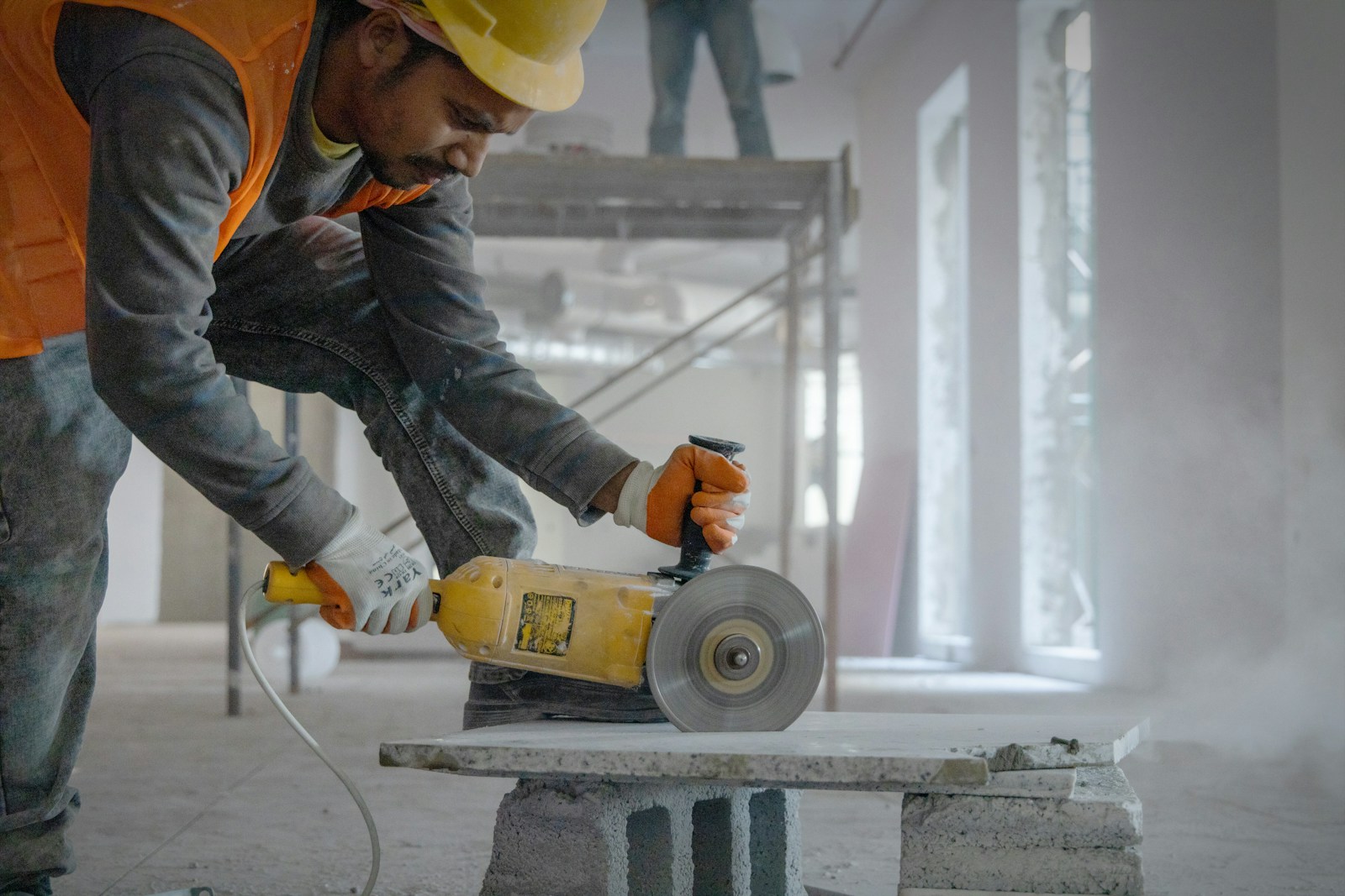 a man using a grinder on a piece of concrete Inside the Modern (construction site): Safety, Innovation, and Efficiency