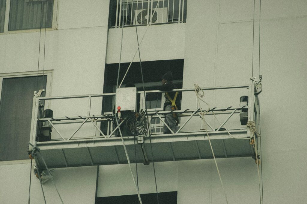 A worker on a suspended scaffold is repairing a building facade.