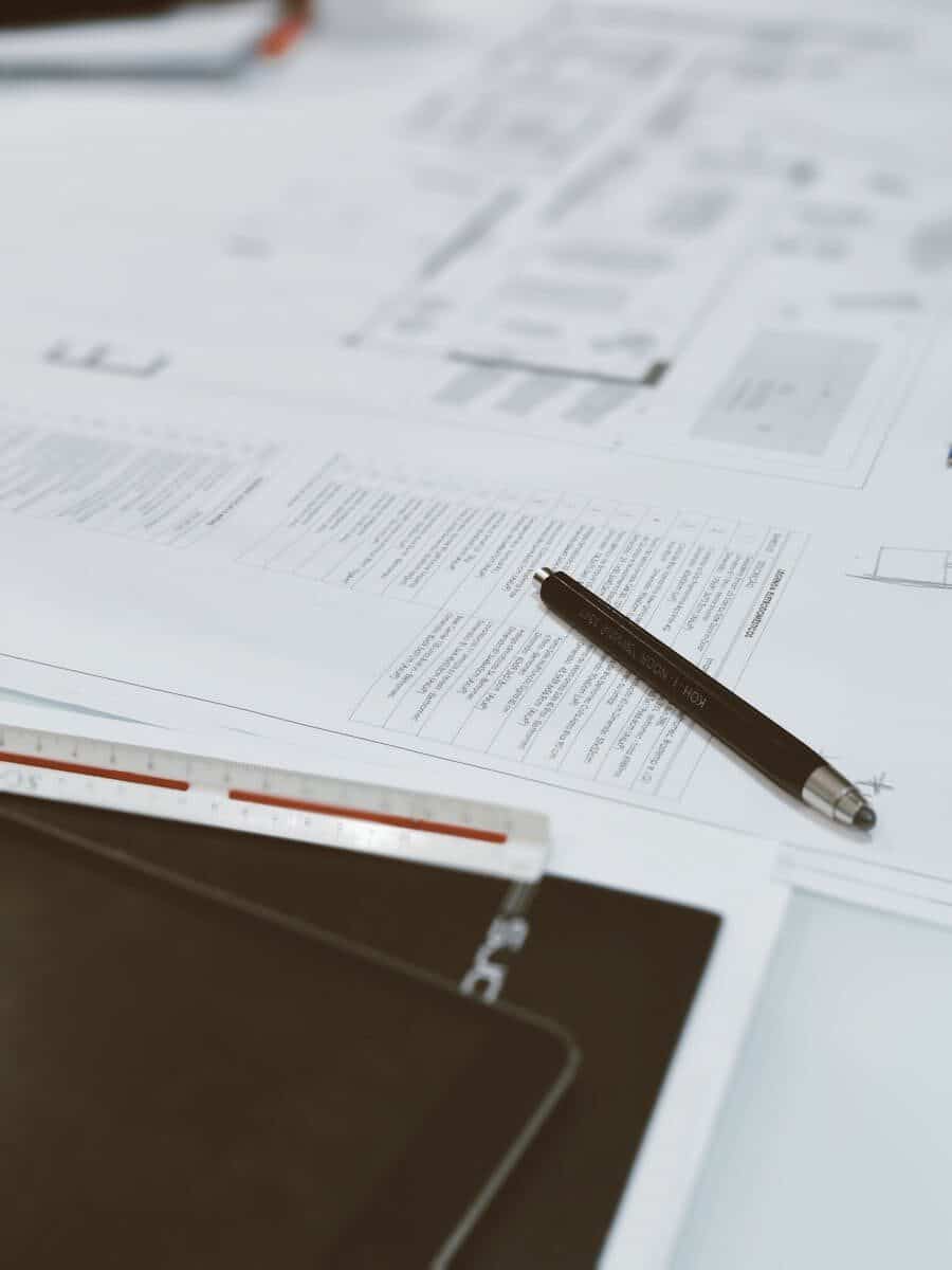 Top view of architectural blueprints, pen, and scale ruler on a designer's desk, showcasing a creative workspace.