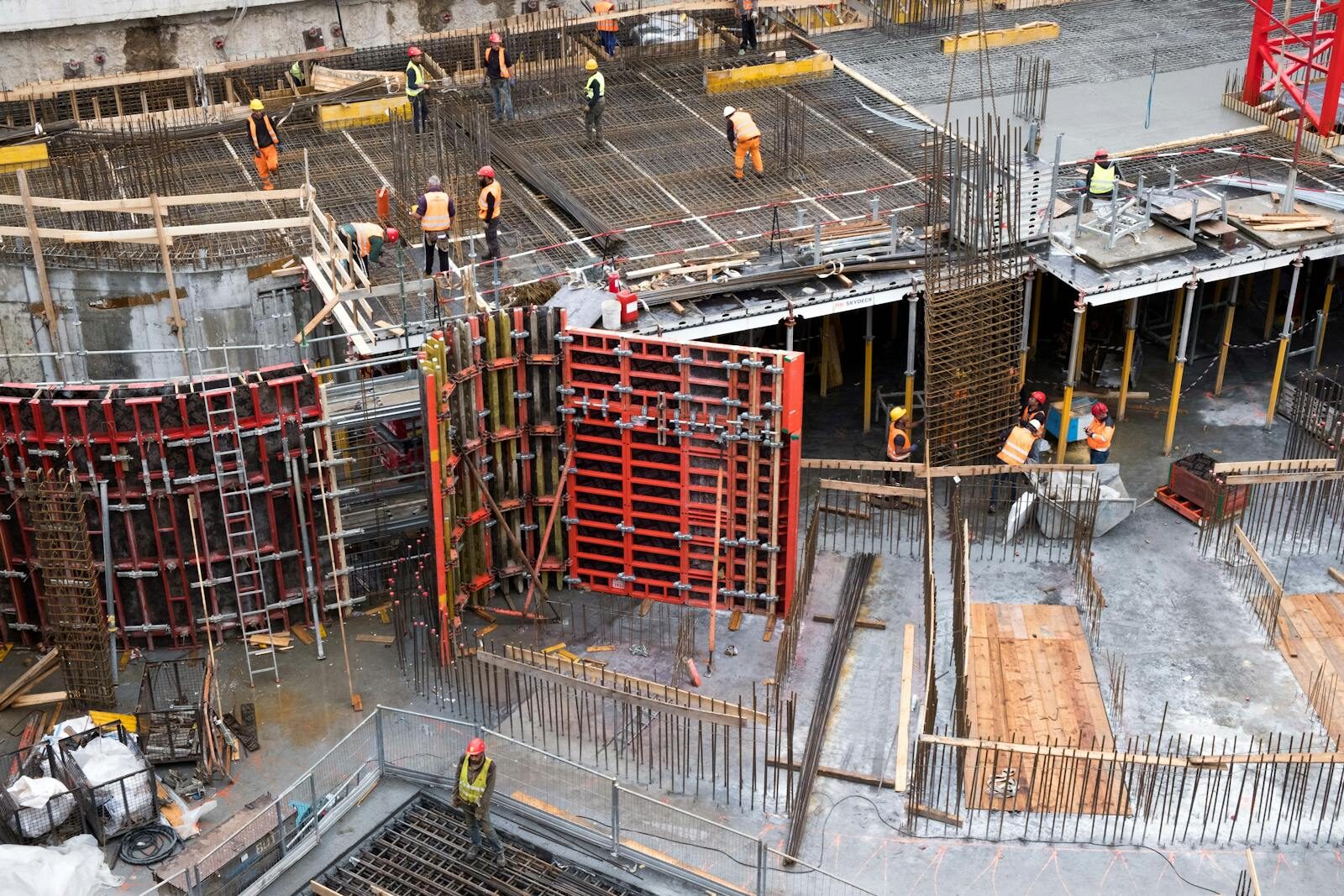 Industrial construction site with workers in high visibility clothing at a steel framework structure.