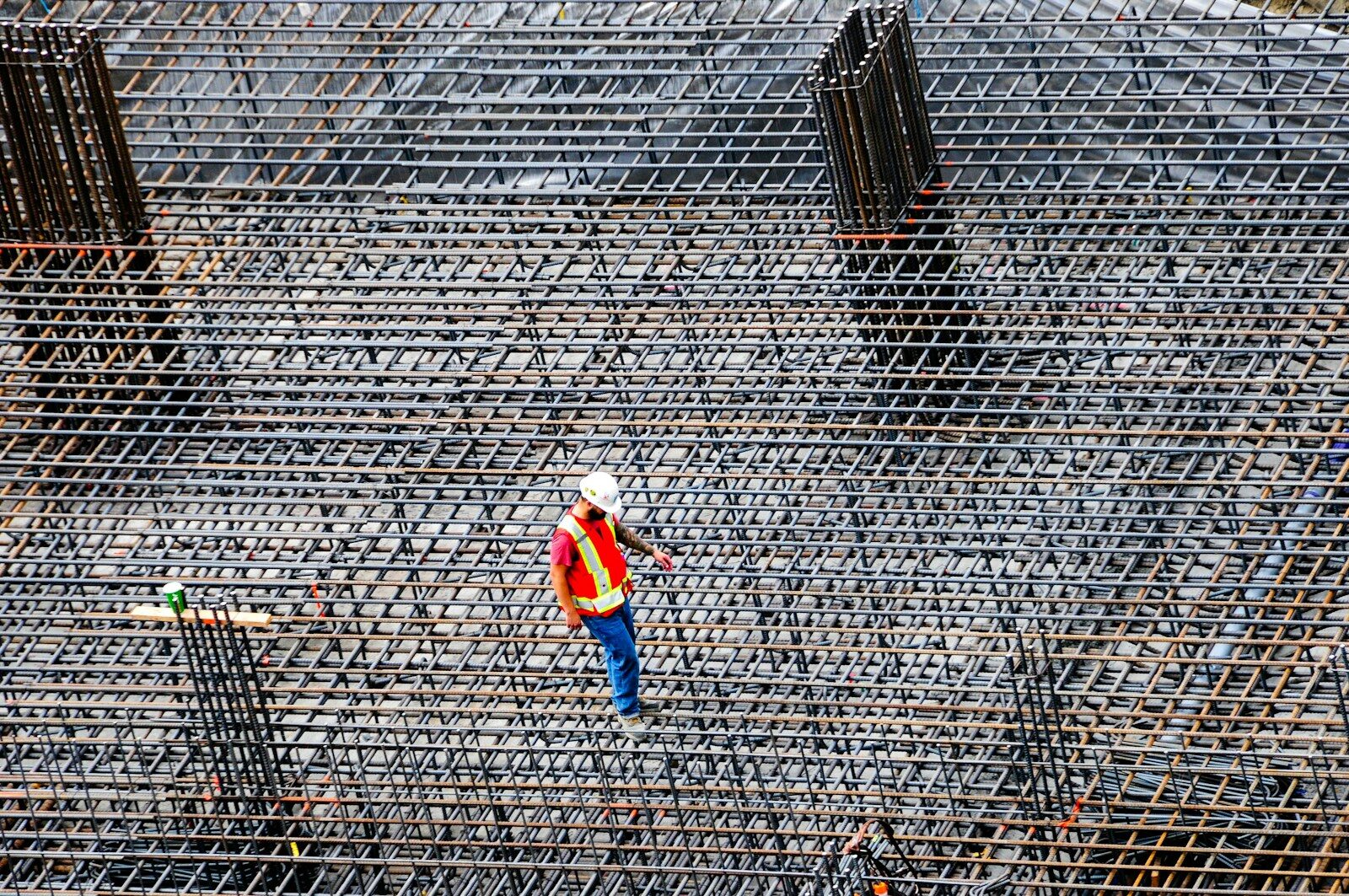 Construction worker inspects rebar on a building site.