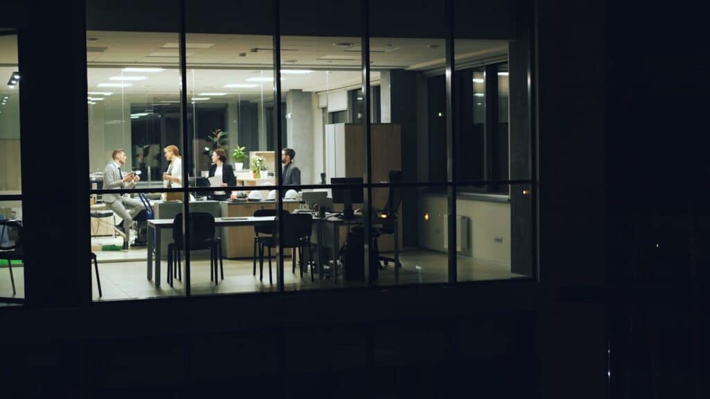 A nighttime office meeting with professionals working in a modern glass-walled office. Top 10 Most Successful Businesses to Start and How the Right Construction Partner Helps