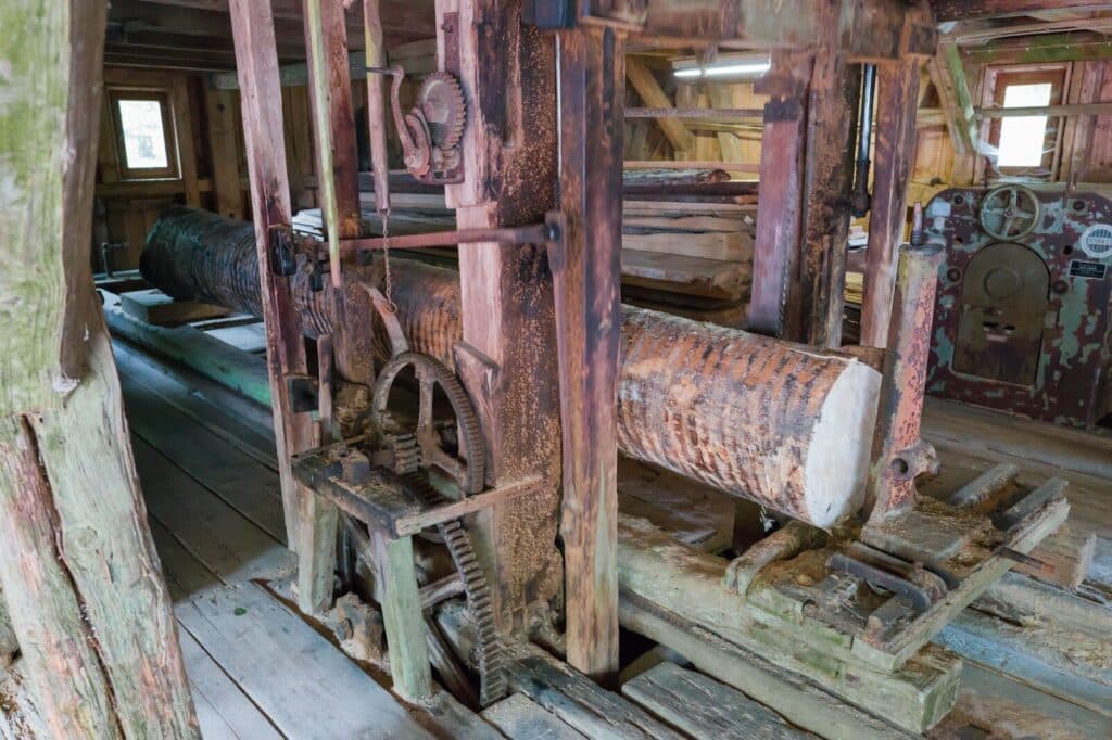 An old, rusty sawmill with logs inside.